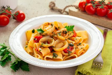 Italian pasta with calamari and tomato sauce. Calamarata is a kind of thick ring pasta paccheri, with sliced squid. Originates from Naples, the South of Italy.