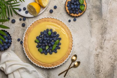 Gri taş masada yaban mersini ve limonlu tart. Üst Manzara. Boşluğu kopyala.