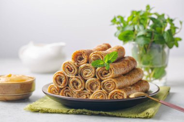 Haşhaş tohumlu tatlı krep sarma piramidi. Naneli, limonlu ve yanında da limonlu. Beyaz arkaplan.