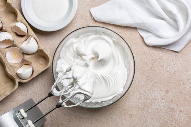 Meringue için çırpılmış yumurta beyazı ve şeker karıştırma kabında elektrikli el çırpma ile karıştırılmış. Mutfak aletleri ile aşçılık süreci.