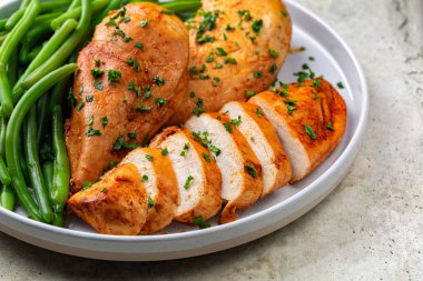 Close-up of oven baked boneless chicken breast made with paprika and parsley,  green beans.