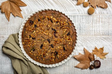 Tuscan vegan autumn chestnut cake Castagnaccio. Made with water, olive oil, pine nuts, rosemary and raisins. Homemade, without wheat flour. 