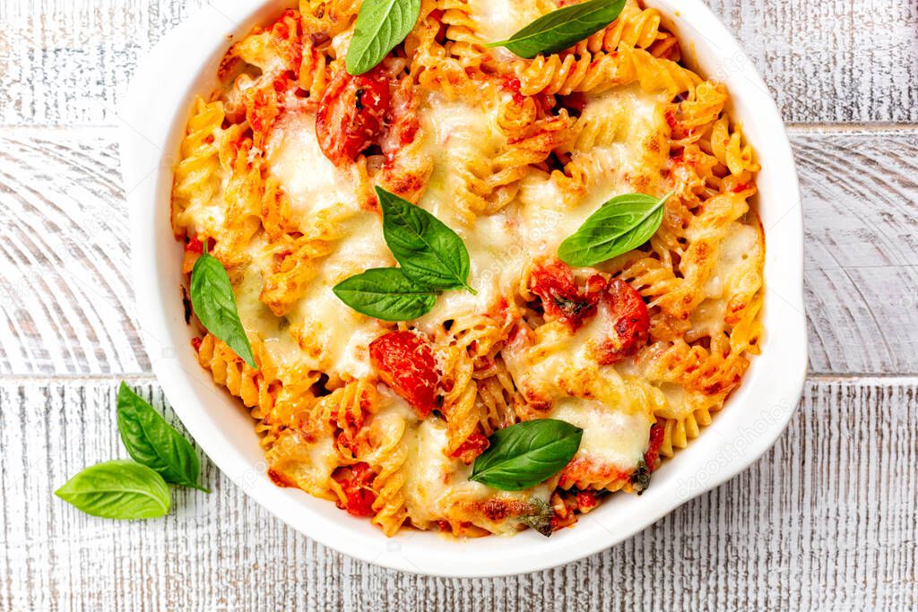 Close up of Pasta alla sorrentina. Spiral shape fusilli pasta oven baked in casserole with tomato sauce, basil and mozzarella, parmigiano cheese. Italian meal, Campania region.