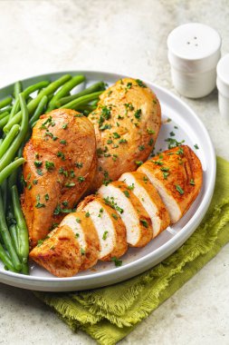 Kırmızı biber ve maydanozdan yapılmış fırında pişmiş kemiksiz tavuk göğsü, yeşil fasulye. Dikey resim.