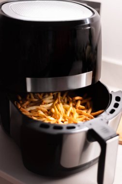Air fryer with french fries on the worktop clipart