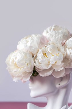 İnsan kafası vazosundaki beyaz şakayıklar.