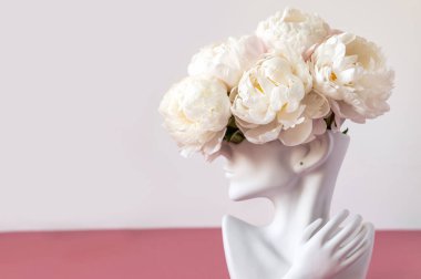 İnsan kafası vazosundaki beyaz şakayıklar.