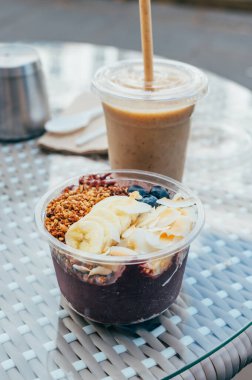 Acai Bowl 'da yabani acai üzümü, muz, jöle ve badem ezmesi var. Standart malzemeler: dilimlenmiş muz, taze yaban mersini, hindistan cevizi cipsi ve ev yapımı glütensiz karabuğday gevreği.