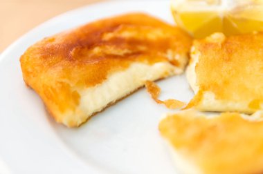 Authentic Greek Fried Cheese, Saganaki, tasty appetizer: crunchy on the outside, melted cheese on the inside. Served with slice of lemon in tavern