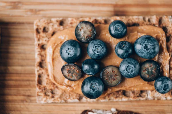 Open sandwich with blueberries. Made from wholegrain crispbreads and peanut butter, healthy nutritious snack option