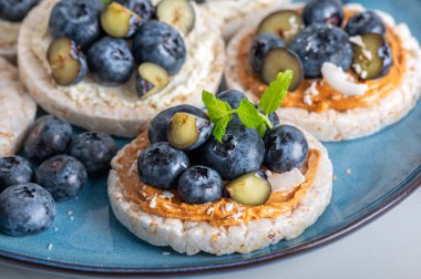 Open sandwich with blueberries. Made from rice crispbreads and peanut butter, healthy nutritious snack option, vegan food