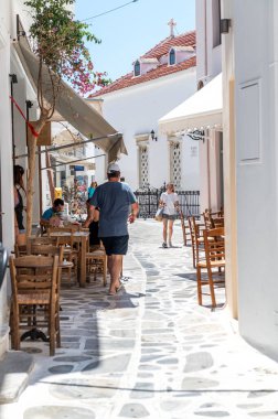 Tinos, Greece: July 17, 2022: City centre and streets of village of Tinos with Cycladic houses and shops on Tinos island, Cyclades, Greece