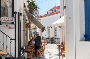 Tinos, Greece: July 17, 2022: City centre and streets of village of Tinos with Cycladic houses and shops on Tinos island, Cyclades, Greece