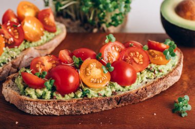 Tasty open sandwich from toasted sourdough bread with mashed avocado and fresh tomatoes