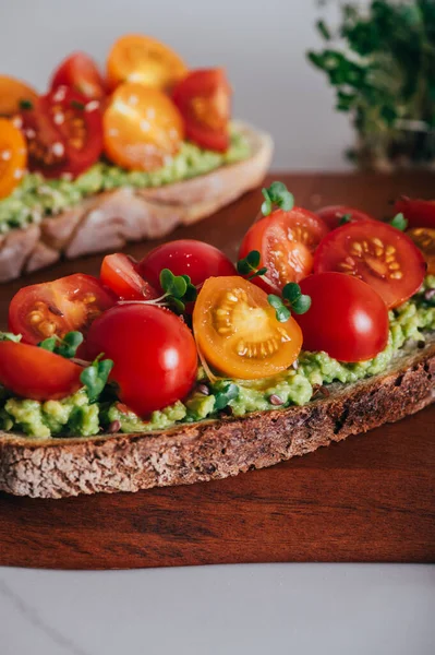 Tasty open sandwich from toasted sourdough bread with mashed avocado and fresh tomatoes