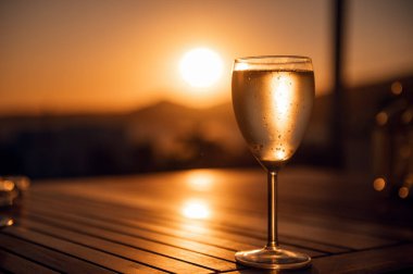 Traditional house white wine served in tavern, traditional greece drink, mazing sunset as background