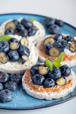 Open sandwich with blueberries. Made from rice crispbreads and peanut butter, healthy nutritious snack option, vegan food