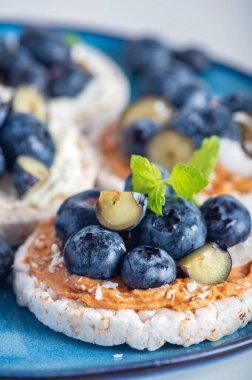 Open sandwich with blueberries. Made from rice crispbreads and peanut butter, healthy nutritious snack option, vegan food