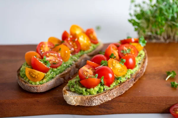 Tasty open sandwich from toasted sourdough bread with mashed avocado and fresh tomatoes