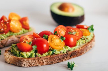Tasty open sandwich from toasted sourdough bread with mashed avocado and fresh tomatoes