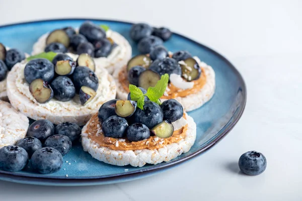 Open sandwich with blueberries. Made from rice crispbreads and peanut butter, healthy nutritious snack option, vegan food