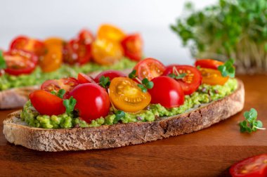 Tasty open sandwich from toasted sourdough bread with mashed avocado and fresh tomatoes