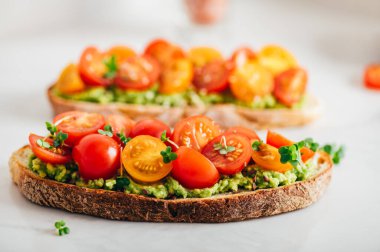 Tasty open sandwich from toasted sourdough bread with mashed avocado and fresh tomatoes