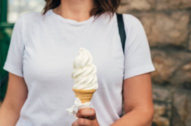 Soft whipped vanilla ice cream with chocolate stick in waffle cone in hands