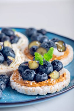 Open sandwich with blueberries. Made from rice crispbreads and peanut butter, healthy nutritious snack option, vegan food