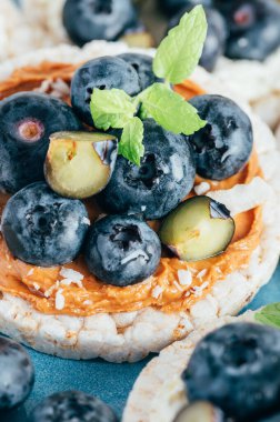 Open sandwich with blueberries. Made from rice crispbreads and peanut butter, healthy nutritious snack option, vegan food