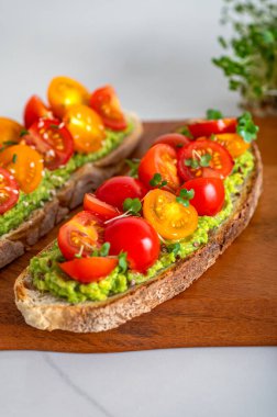 Tasty open sandwich from toasted sourdough bread with mashed avocado and fresh tomatoes