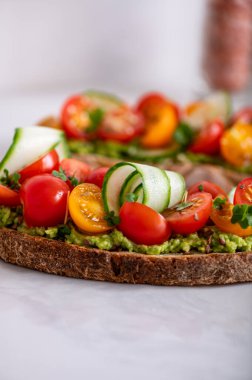 Tasty open sandwich from toasted sourdough bread with mashed avocado and fresh tomatoes