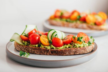 Tasty open sandwich from toasted sourdough bread with mashed avocado and fresh tomatoes