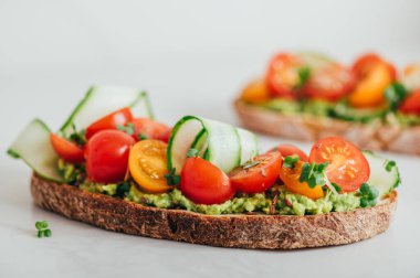 Tasty open sandwich from toasted sourdough bread with mashed avocado and fresh tomatoes