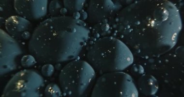 Mavi boya kabarcıkları suda zıplıyor.