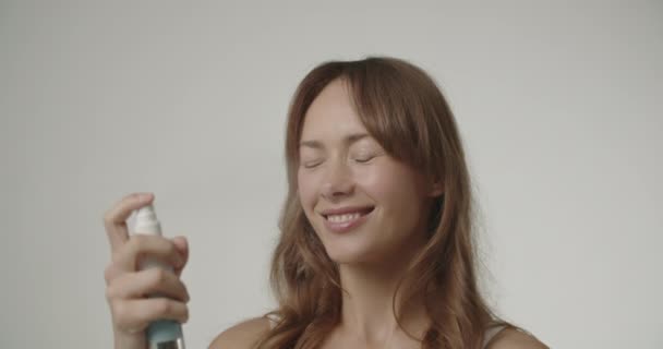 Schöne junge Frau wendet erfrischendes Spray an — Stockvideo