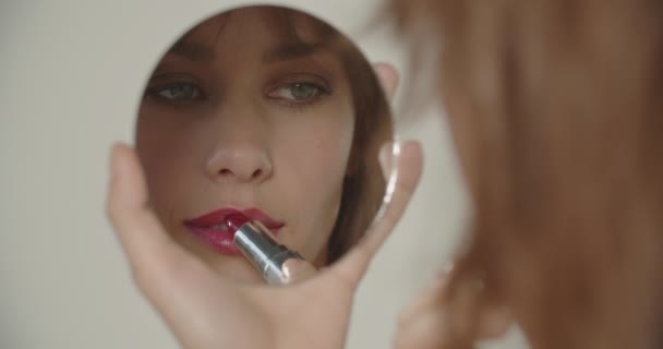 Vacker ung kvinna som innehar spegel för att applicera läppstift — Stockvideo