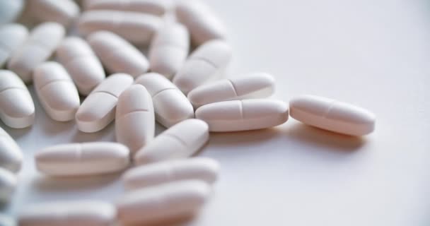 Högen med vita tabletter på vit bakgrund — Stockvideo
