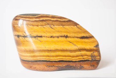 Altın renkli, yarı değerli taş Jasper. Makro. Portakal sarısı çizimli mineral. Beyaz arkaplanda gölgeli tek taş.