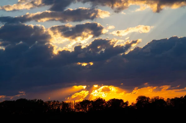 Windy sunset with black clouds. Natural real background with the last rays of the sun cloud. Colorful sky with sunset over forest silhouette.Sunset with black clouds. Natural real background with the last rays of the sun cloud.