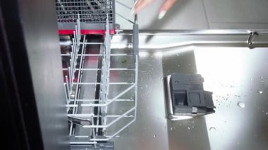 Bulaşık makinesine bulaşıkları yükleyen bir kız bulaşık makinesi, bulaşık makinesi, bulaşık makinesi, bulaşık makinesine yakın çekim, bulaşık makinesini dolduran ve kapayan bir kadın.