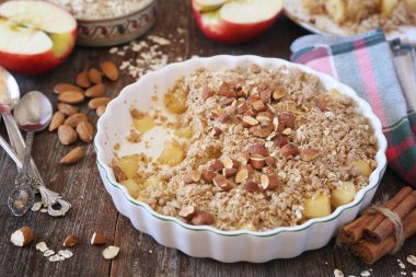 Yulaf ezmesinden taze elma parçacıkları, ahşap arka planda sağlıklı kahvaltı için badem sosu, köy tarzı.