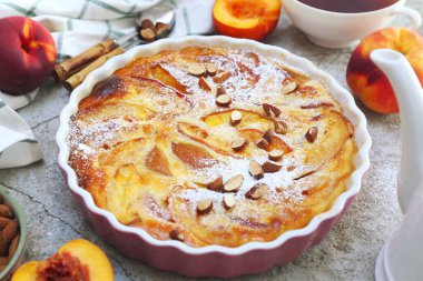 Bademli nektarin clafoutis (turta), kremalı şeker sosu ve bir fincan çay, açık arkaplanda Fransız mutfağı