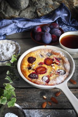 Damson mavisi erik pudingi (turta) ve bir fincan çay, krema şekeri ve badem sosu, ahşap zemin üzerinde Fransız mutfağı. Kırsal biçim