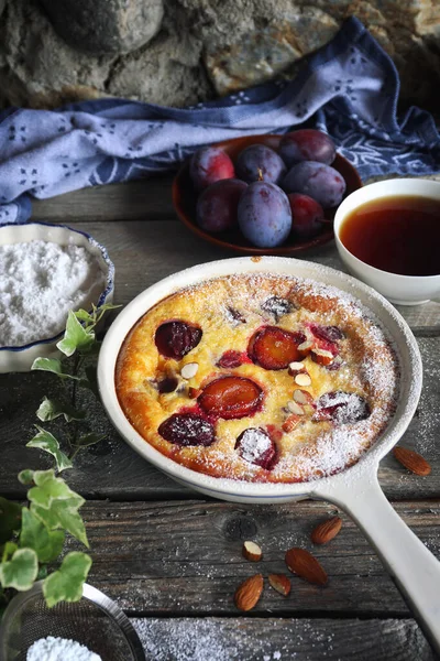Damson mavisi erik pudingi (turta) ve bir fincan çay, krema şekeri ve badem sosu, ahşap zemin üzerinde Fransız mutfağı. Kırsal biçim