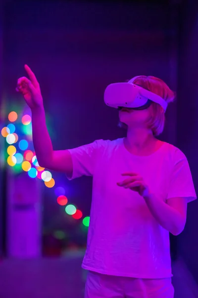 Focused female interacting with virtual reality. Future technology concept. Colorful neon lights.