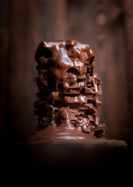Melted hot chocolate dripping over a pile of chocolate bars on a rustic wooden table