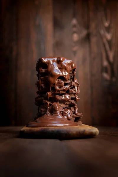 Melted hot chocolate dripping over a pile of chocolate bars on a rustic wooden table