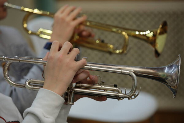 Playing the trumpet of two instruments gold and silver hands fingers close up musical background