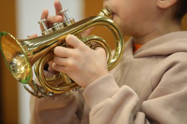 Küçük trompetçi çocuk altın bir enstrüman üflüyor